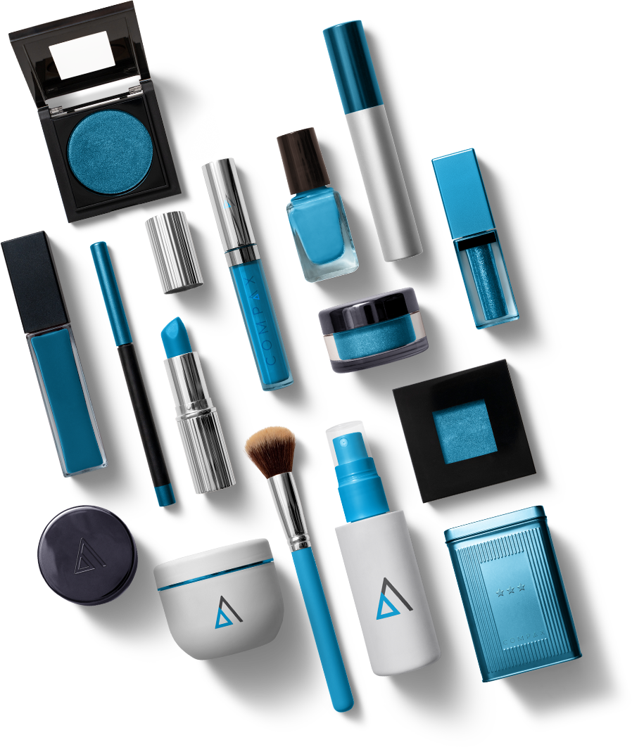A variety of blue-themed makeup products arranged on a white background. Items include eyeshadow, nail polish, mascara, lip gloss, lipstick, foundation, and brushes. Many products have blue casings and branding, emphasizing a cohesive color palette.