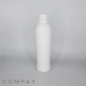 A plain, white, empty plastic bottle stands upright against a light gray background. The bottle has a smooth surface with a slightly curved shape, and its screw cap is missing. The word "COMPAX" is written at the bottom left corner of the image.