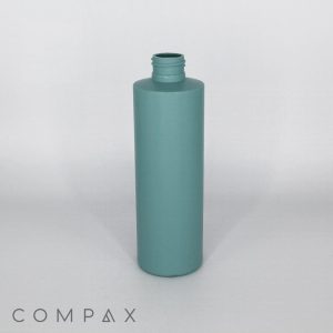 A tall, cylindrical teal bottle with a screw-top opening is positioned upright against a plain white background. The brand name "COMPAX" is printed in the lower left corner.
