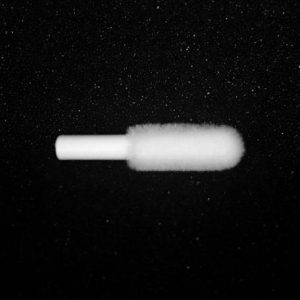 A single Nylon Flocking Applicator with a white handle lies horizontally against a black, slightly textured background. The applicator's tip appears soft and fuzzy, contrasting with the dark backdrop.