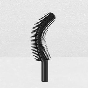 A Plastic Brush Applicator with a curved black wand and evenly spaced bristles is standing upright against a light, textured background. The wand is designed to help apply mascara to eyelashes, providing volume and curl.