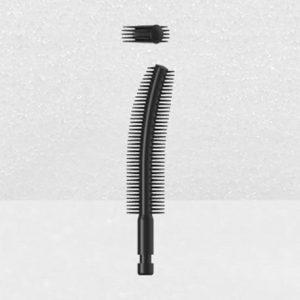 A Plastic Brush Applicator, featuring fine bristles and separated into two distinct parts, lies against a plain, light-colored background. The larger, curved section of the brush is at the bottom, while the smaller, straight section is positioned above it.