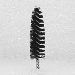 A detailed close-up image features the Nylon Brush Applicator, showcasing its cylindrical shape and dense black bristles arranged spirally around a slender, twisted metal rod. The background is a plain white with a subtly textured appearance.