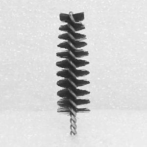 The Nylon Brush Applicator is a small cylindrical brush with tightly packed bristles, similar to a bottle brush. It features a metal twisted wire handle, and the bristles form a helical pattern around the wire against a plain, light-colored background.