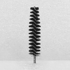 The Nylon Brush Applicator, featuring a small cylindrical shape with black bristles and a twisted metal handle, is displayed against a textured, speckled white background. The brush stands upright with its bristles fanning out in a spiral pattern.