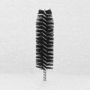 A product named "Nylon Brush Applicator," featuring a narrow, cylindrical shape and black bristles with a twisted metal handle, stands upright against a plain white background.