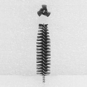 The Nylon Brush Applicator, with its vertical cylindrical design and stiff bristles, stands against a plain background. A separate cluster of bristles is suspended above it, resembling a detached component of the main brush.