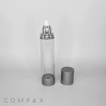 A clear, cylindrical spray bottle with silver accents, featuring a spray nozzle on top and an additional silver cap beside it on a light gray background. The word "COMPAX" is visible at the bottom left corner of the image.