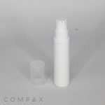 A white, cylindrical pump bottle with a clear plastic cap off and placed beside it, standing on a plain gray surface. The logo "COMPAX" is visible in the bottom left corner.