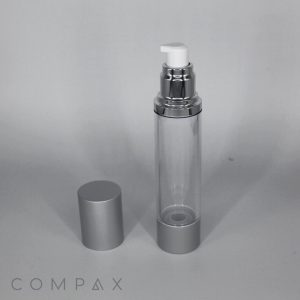 A clear, cylindrical pump bottle with a silver base and cap. The cap is removed, placed beside the bottle, and reveals a white pump dispenser. The background is plain, and the brand name "COMPAX" is visible in the bottom left corner.