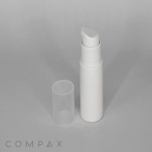 A white cylindrical pump bottle with a clear cap removed, placed beside it. The bottle has a sleek design and is set against a plain light grey background. The word "COMPAX" is printed in grey at the bottom left corner of the image.
