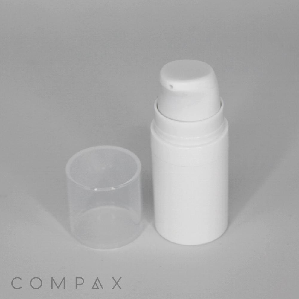 A white, airless plastic bottle with a pure pump spring, featuring a transparent cap placed beside it, set against a plain gray background. The base of the image displays the word "COMPAX" in capital letters.