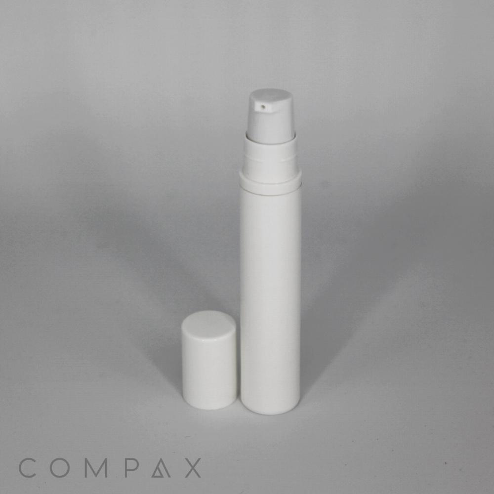 A white cylindrical bottle with a pump dispenser and a removable cap standing on a gray surface. The bottle is upright, and the cap is placed in front of it. The word "COMPAX" is faintly visible in the bottom left corner.