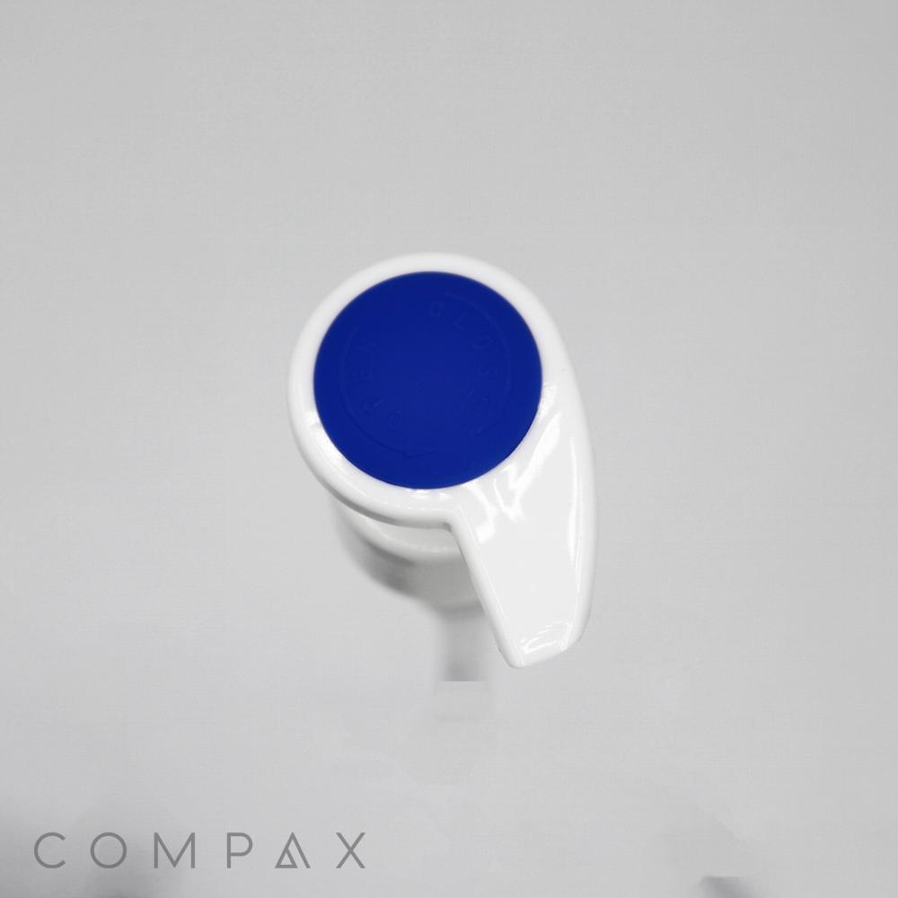 A white plastic pump with a silicone blue top, viewed from above, set against a plain grey background. The bottom left corner has the word "COMPAX" written in a light grey, modern font.