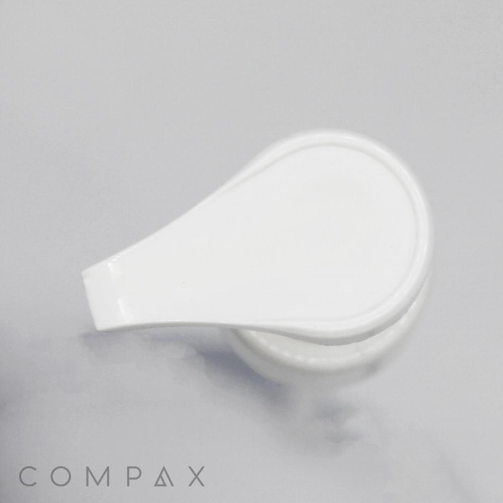 Overhead view of a white plastic Teardrop Pump dispenser on a light background. The dispenser is closed, and the brand name "COMPAX" is visible in grey text near the bottom left corner.