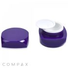 An image of a purple cosmetic container with a removable lid is shown. On the left, the container is closed, displaying its shiny surface. On the right, the container is open, revealing a white inner lid. The brand name "COMPAX" appears at the bottom.