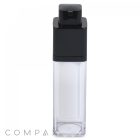 A clear, square bottle with a black pump dispenser at the top. The bottle is empty, and the transparent lower part contrasts with the opaque black top. The word "COMPAX" is partially visible in the bottom left corner of the image.