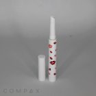 A white cylindrical lip balm container decorated with red lipstick kiss marks, standing upright on a plain background. The cap is removed and placed beside it. The word "COMPAX" is marked on the bottom-left corner of the image.