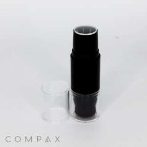 A black cylindrical Dual Stick + Blender cosmetic tube stands upright with the cap removed and placed beside it on a white background. The logo "COMPAX" is visible at the bottom left corner of the image.
