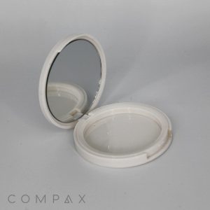 A Single Well Square Compact with a white plastic casing is open, revealing the reflective surface on one side and an empty round compartment on the other. The brand name "COMPAX" is visible in the lower left corner of the image.