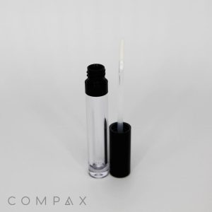 The "Round Lip Gloss Bottle," featuring a clear tube and black screw cap, is displayed with the applicator wand removed and positioned next to it. The wand boasts a white sponge-tip applicator. The brand name "COMPAX" is visible in the bottom left corner of the image.