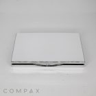 A closed Rectangular Compact with Mirror, featuring a slim, metal case with a smooth and shiny surface, complete with a small latch at the front. The background is plain white, and the word "COMPAX" is displayed in gray letters at the bottom left corner.