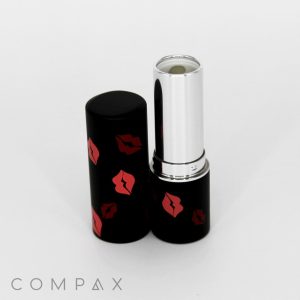A black tube of Round Lipstick features red lips designs. The silver-colored lipstick is partially extended and stands next to the cap. The brand name "COMPAX" is visible at the bottom of the image.
