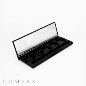 An open black 5 Pan Rectangular Compact with a mirror on the inside of the lid. The palette includes five empty circular slots designed for holding makeup products. The brand name "COMPAX" is displayed in the bottom left corner on a white background.
