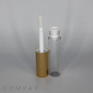 A Round Lip Gloss Bottle with a clear tube and a shiny gold cap stands upright, with the cap removed and placed nearby. The attached applicator wand with a white tip is visible, partly inserted into the open tube. The background is plain and light gray. The word "COMPAX" appears at the bottom.