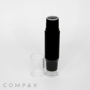 A black cylindrical container with a removable clear plastic cap labeled "Round Dual Stick + Blender Pen" is standing upright on a white background. The brand name "COMPAX" is printed at the bottom left corner of the image.