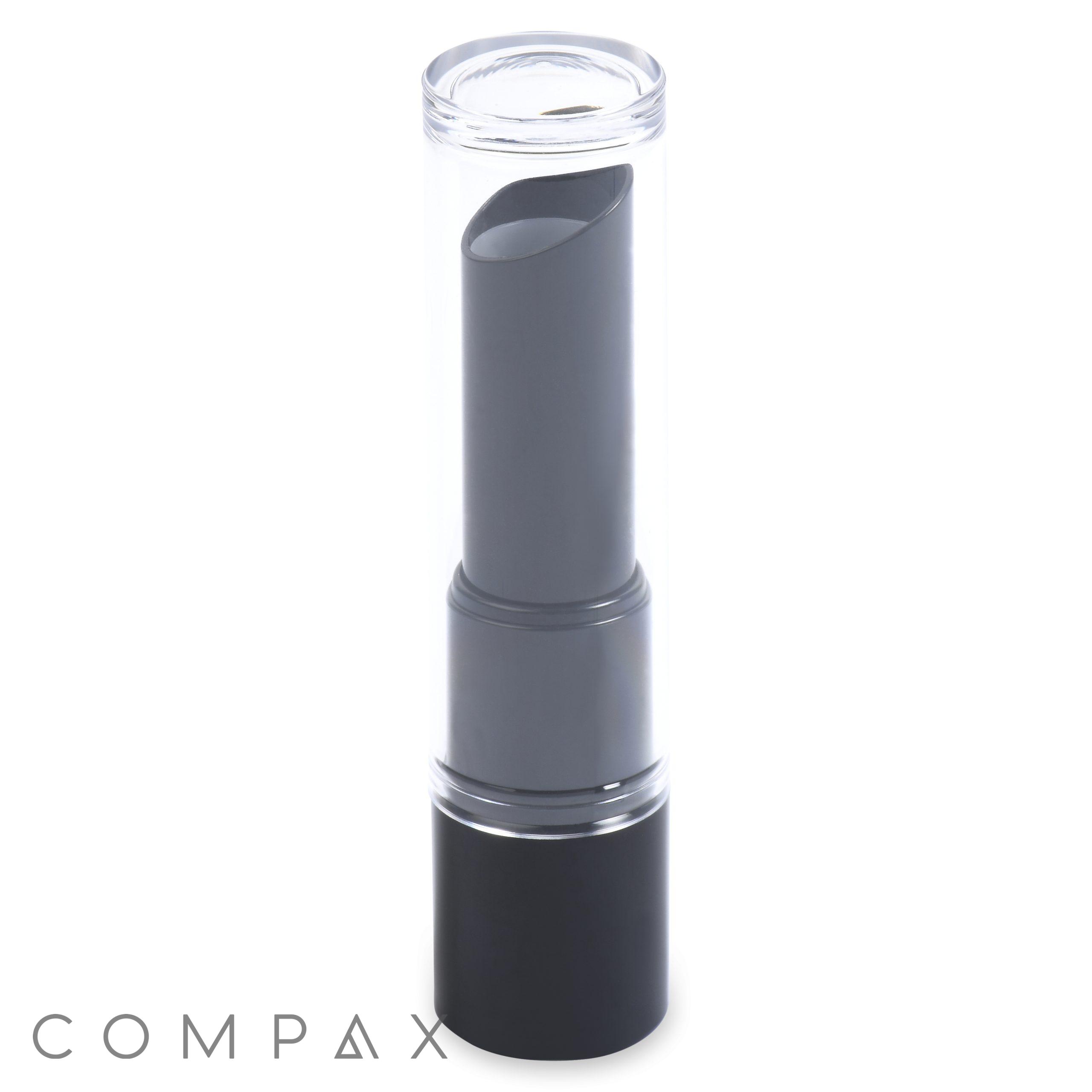 A Round Lipstick in black is enclosed in a clear cylindrical tube on a white background. The brand name "COMPAX" is displayed in grey letters at the bottom left of the image.
