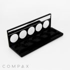 An open "5 Well Rectangular Compact with Windows" makeup palette in black, featuring five empty circular slots for powders or eyeshadows, and a mirror along the inside of the lid. The brand name "COMPAX" is printed in light gray at the bottom left corner of the image.