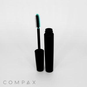 A Fluted Round Mascara Bottle with its molded brush wand removed and standing upright next to it, resting on the opened bottle. The bristles of the brush are tinted green. The word "COMPAX" is visible at the bottom left corner of the image.