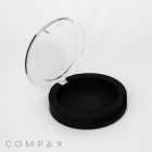 A Single Well Round Compact case, featuring a round, black design and a transparent lid that opens easily, is showcased against a white background. The brand name "COMPAX" is elegantly written in grey letters at the bottom left corner.