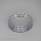 A transparent, round plastic container, named the Single Well Round Compact, with a clear lid sits on a gray surface. The container looks empty, and the word "COMPAX" is visible in the bottom left corner of the image.
