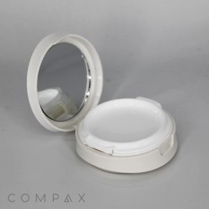 An open Round Cushion Compact with Mirror in a white case, revealing an empty compartment for makeup or powder. The mirror is on the inner lid. The word "COMPAX" appears in the bottom left corner of the image, set against a light grey background.