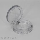 A Single Well Round Compact cosmetic case is open with its lid tilted back, revealing the inner compartment designed for makeup. The background is plain white, and the brand name "COMPAX" is visible at the bottom left.