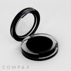 A Single Well Round Compact with a transparent lid, displayed open in black and clear. The compact appears to be empty. The word "COMPAX" is printed in light grey at the bottom left corner of the image, set against a plain white background.