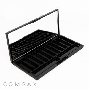 An 11 Well Rectangular Compact in sleek black, featuring an open case design with multiple empty compartments and a large built-in mirror. Positioned on a white background, the palette showcases the brand name "COMPAX" in the bottom left corner.