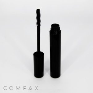 A Round Mascara Bottle in black is open, with the applicator wand placed to its left. The sleek and glossy design of the product stands out against the white background. The word "COMPAX" is clearly visible in the lower left corner.