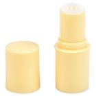 A yellow, cylindrical Mini Stick twist-up container with its cap removed, revealing the product inside. The cap is standing upright next to the container. The brand name "COMPAX" is positioned at the bottom left corner of the image.