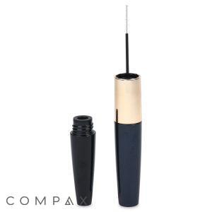 A black Dual Fluted Round Mascara Bottle with a gold accent is pictured with its cap off, revealing the slender brush of the mascara wand. The brand name "COMPAX" is visible in gray text in the bottom left corner. The tube and cap are vertically aligned against a clean white background.