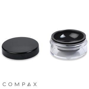A small, clear acrylic jar labeled as a "16.5ml Powder Sifter Jar" with a black lid placed next to it. The container appears to be empty and is commonly used for storing cosmetics or other small items. The word "COMPAX" is written at the bottom left corner.