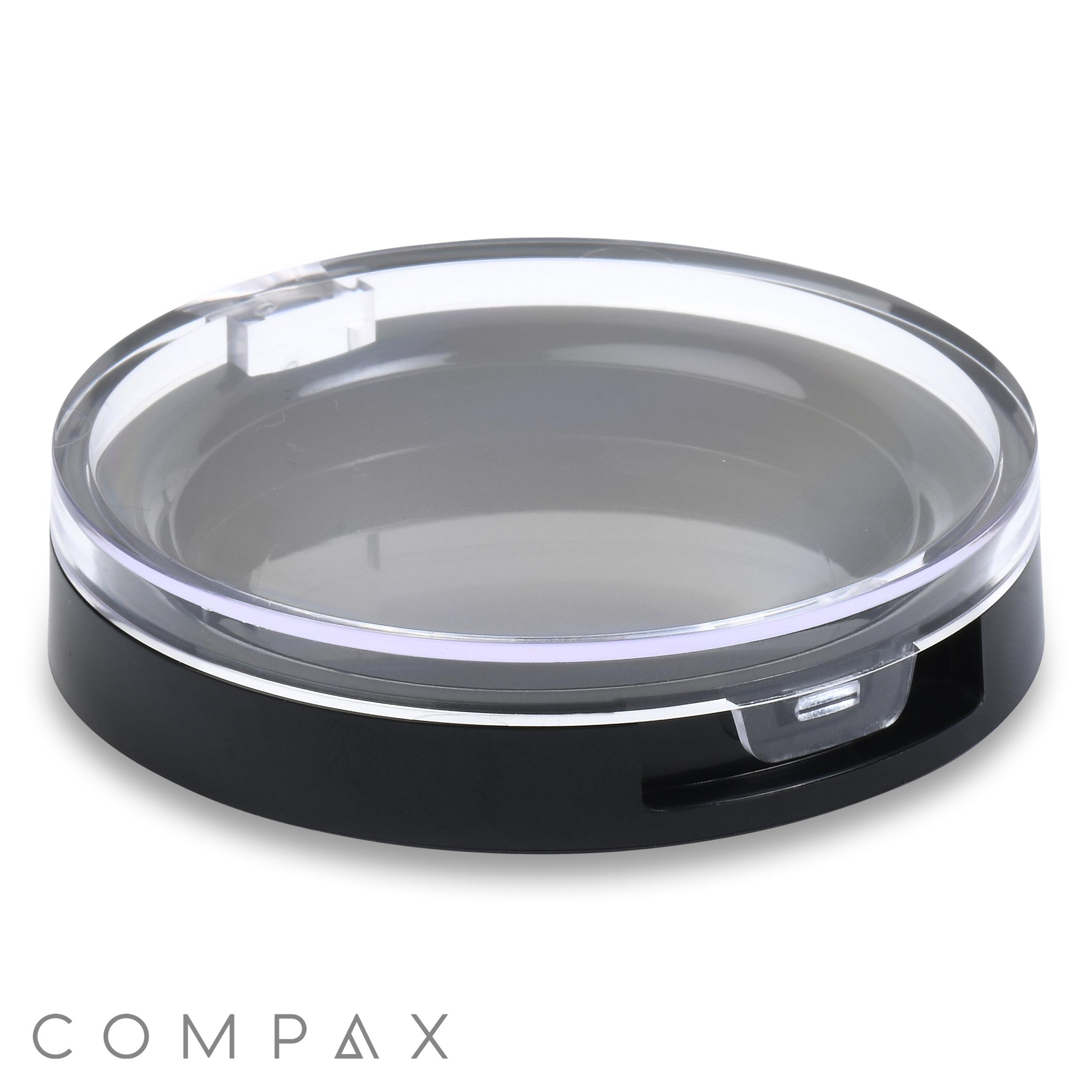 A Round Compact with a clear, transparent lid and a black base, featuring the COMPAK logo in the bottom left corner.