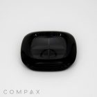 A small, black, square-shaped object with a glossy finish and rounded edges is centered against a plain white background. The word "COMPA" is partially visible in the bottom left corner of the image.