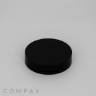 A black, round compact case with a smooth, matte finish is placed against a plain white background. The word "COMPAX" is printed in light gray, modern font in the bottom-left corner.