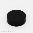 A sleek, round, black compact case is displayed against a white background. The case has a flat top and a short, cylindrical shape. The word "COMPAX" appears in gray, minimalist text at the bottom left corner of the image.