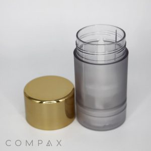 A cylindrical container featuring a golden cap is shown with the cap removed. The container itself is translucent gray, allowing a glimpse of its interior. The brand name "COMPAX" is visible at the bottom of the image.