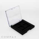 A black compact case with a transparent lid is displayed. The interior features four square compartments, each with a grid-like textured pattern. The word "COMPAX" is printed on the bottom left of the image.