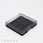 A square compact makeup case with a clear lid, displaying four evenly spaced compartments inside. The lid has a grid pattern, and the case is closed. The word "COMPAX" is printed in gray at the bottom left corner. The background is white.